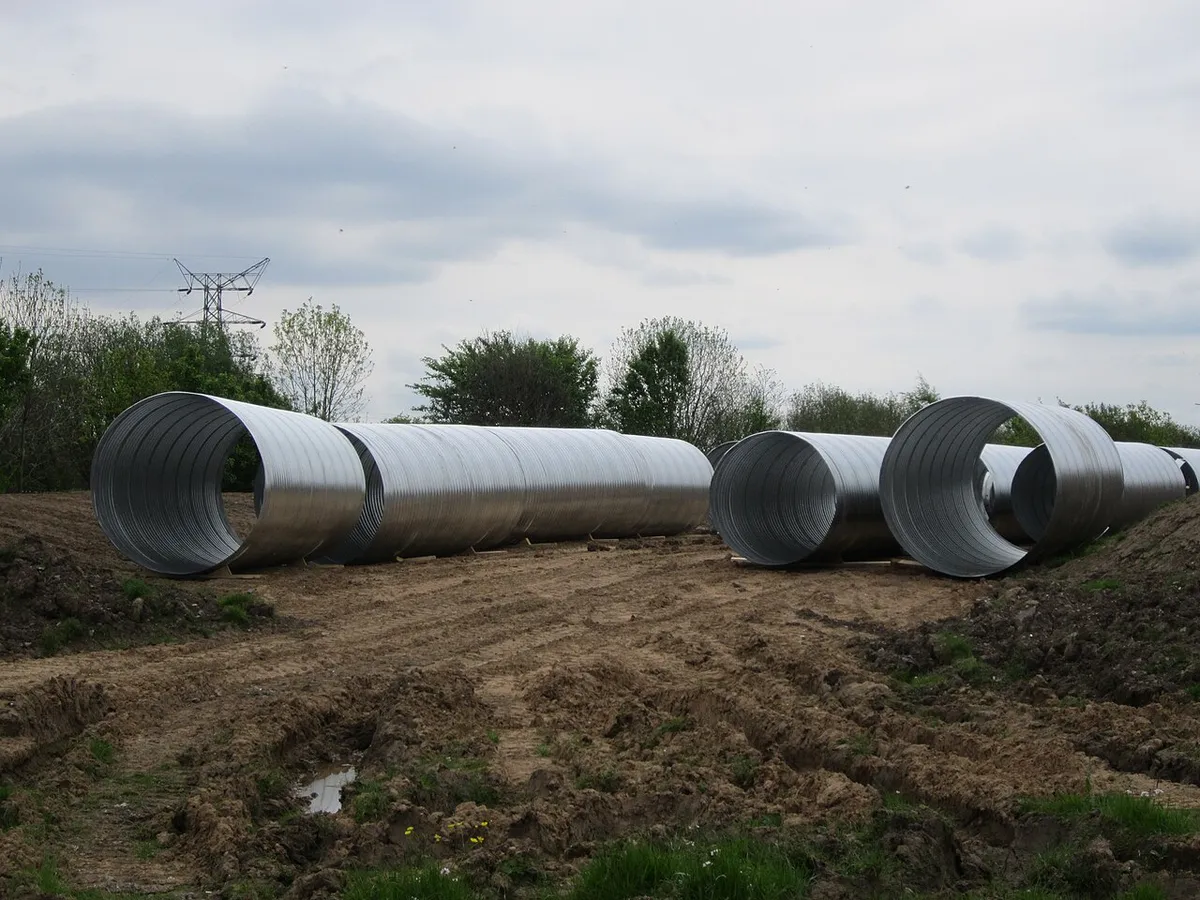 Galvanized corrugated steel culvert pipe sections on a dirt work site