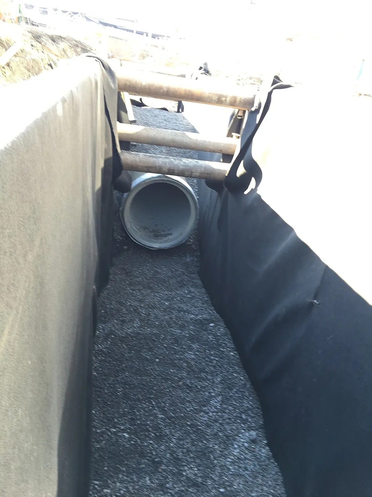 A pipe laid in a narrow shored trench on a bed of crushed stone